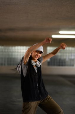 Gülümseyen genç kadın dans ediyor, otoparkta hip hop hareketi yapıyor. Hobi ve aktif yaşam tarzı konsepti.
