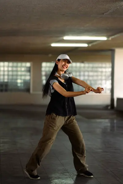 Full length of talented female street dancer dancing in parking garage.