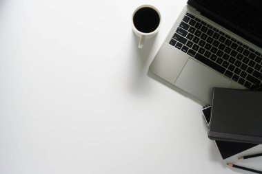 Laptop bilgisayarı, kahve fincanı ve defterleri olan ofis masası. Kopyalama alanı olan üst görünüm.