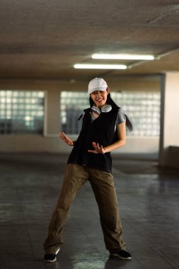 Otoparkta hareketli hip hop hareketleri yapan uzun boylu genç bir kadın..