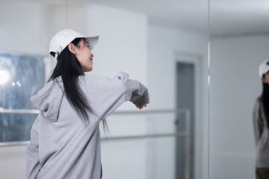 Gülümseyen genç bir kadının geniş bir dans stüdyosunda break dans çalışması..