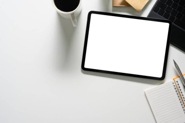 Dijital tableti, bilgisayarı, kahve fincanı ve not defteriyle üst kattaki ofis masasında. Reklam için boş ekran.