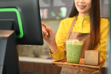 Gülümseyen garson, kahve dükkanında müşteri ödemelerini kabul etmek için kasiyeri kullanıyor..