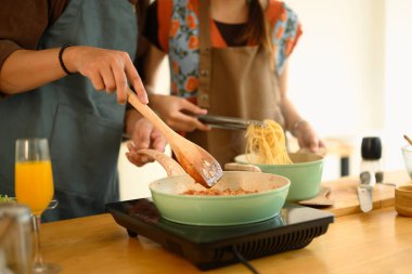 Mutfakta akşam yemeği için leziz bolonez sosu yapan genç çiftin kırpılmış görüntüsü..