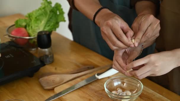年轻夫妇的手把大蒜剥落在木板上 健康生活方式概念 — 图库视频影像