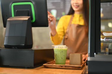 Tezgahta duran bayan garson, kahve dükkanında müşteri ödemelerini kabul etmek için yazar kasayı kullanıyor..