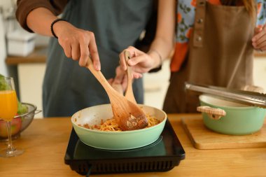 Mutfakta akşam yemeği için leziz bolonez sosu yapan genç çiftin kırpılmış görüntüsü..