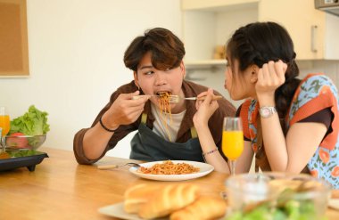 Sevgi dolu genç bir çift mutfakta yemek yiyor, spagetti yiyor. İnsanlar, ilişkiler ve yemek kavramı.