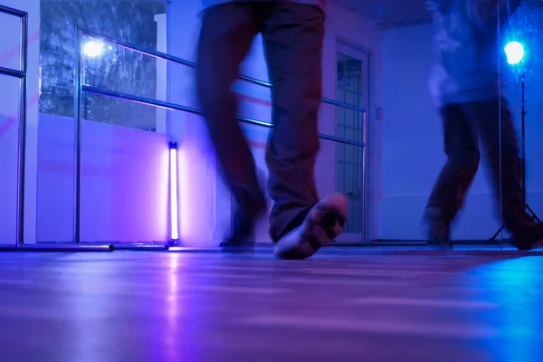 Low section of hip hop dancers legs dancing in studio with neon lights.
