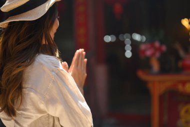 Çin tapınağındaki bir tapınakta dua eden kadın turistin yan görüntüsü..