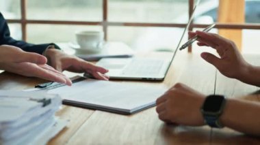 Tanımlanamayan, takım elbiseli bir erkek sigorta acentesi müşteriye kontrat belgesini işaret ediyor..