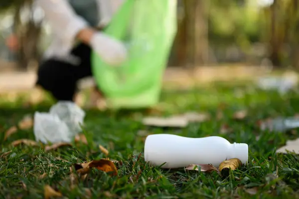 公園でゴミを集めるぼやけで草の上に散らばっているプラスチックボトル 環境ケアコンセプト — ストック写真