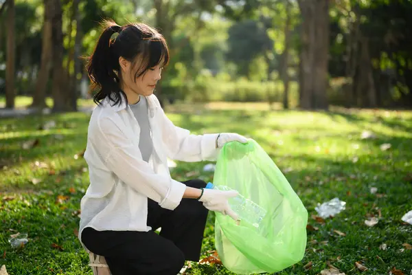 公園でペットボトルを集めている若い女性の笑顔 環境責任の概念 — ストック写真