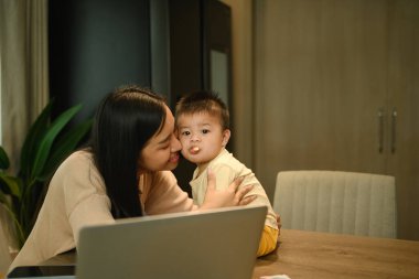 Küçük oğlunu öpen Asyalı bir anne. Annelik ve çocuk bakımı kavramı.