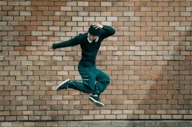 Sokaklarda dans eden ve tuğla duvara zıplayan hip hop dansçılarının tüm vücudu..