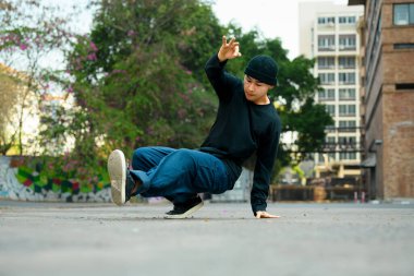 Yetenekli Asyalı erkek dansçı sokakta hip hop dansı yapıyor..