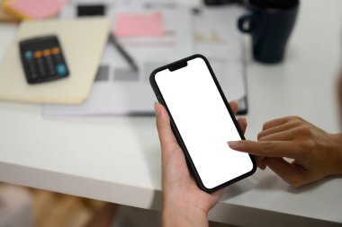 Ofis masasında oturan, elinde akıllı telefon olan iş kadınının yakın plan fotoğrafı..