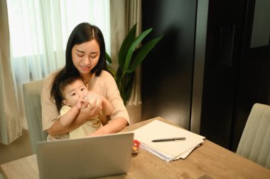 Evde uzaktan çalışırken annesine biberondan bebeğine süt içiriyor..