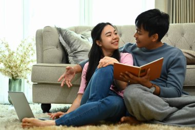 Güzel genç çift yerde kitap okuyor ve hafta sonunu evde birlikte geçiriyorlar..