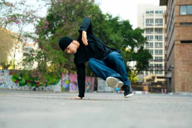 Hip-hop dansçısı şık kıyafetler içinde şehir sokaklarında dans ediyor..