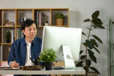 Konsantre olmuş mimar adamlar bilgisayar ekranına bakıyor, ofisinde proje üzerinde çalışıyorlar..