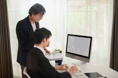 Orta yaşlı işadamı ofiste genç meslektaşlarıyla yeni bir strateji planlıyor.