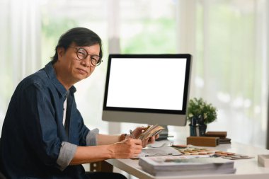 Kendinden emin erkek tasarım uzmanı boş bilgisayar monitörünün önünde çalışıyor..