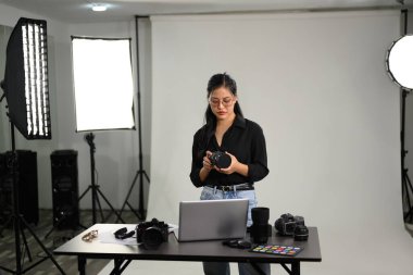 DSLR kamerasıyla profesyonel fotoğraf stüdyosunda çalışan şık bir kadın..