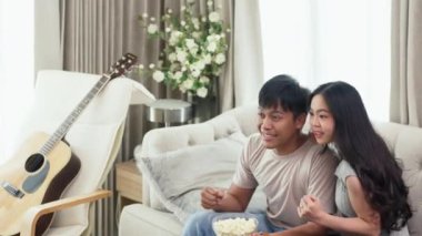 Heyecanlı genç bir çift kanepede oturuyor ve TV 'de spor maçı izliyorlar..