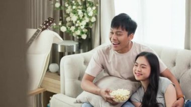 Genç çiftin koltukta oturup TV 'de film izlediği ve patlamış mısır yediği yavaş çekim..