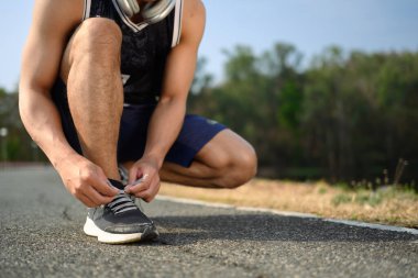 Spor ayakkabısı bağlayan sporcu koşuya ya da kardiyo antrenmanına hazırlanıyor. Sağlıklı yaşam tarzı kavramı.