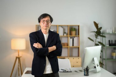 Kendine güvenen orta yaşlı iş adamının portresi çalışma masasının karşısında duruyor ve kameraya bakıyor..