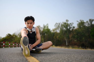 Sportif adam gerinme egzersizleri yapıyor. Parktaki sabah antrenmanına hazırlanıyor..