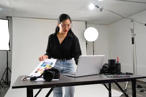 stock image Beautiful young photographer using laptop in modern photo studio.