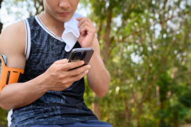 Sporcu açık hava eğitiminden sonra cep telefonu kullanıyor ve dinleniyor..