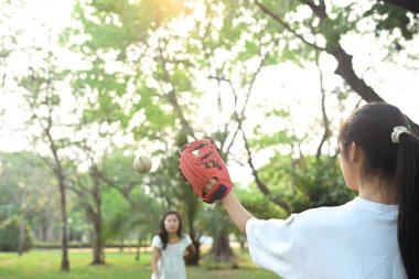 Anne ve kızı halk parkında beyzbolda oynuyor. Aile, spor ve eğlence etkinliği konsepti.