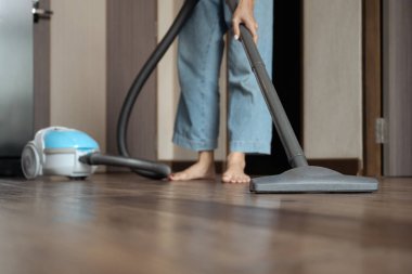 Mutfak zeminini süpüren genç ve mutlu bir kadın. Oda servisi kavramı.