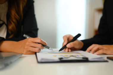 Ofis masasındaki borsa bilgilerini analiz eden iş adamlarının yakın çekim görüntüleri..