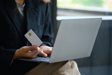 Kredi kartı tutan ve dizüstü bilgisayar kullanan iş kadını ödemeyi yapıyor veya internetten sipariş veriyor..