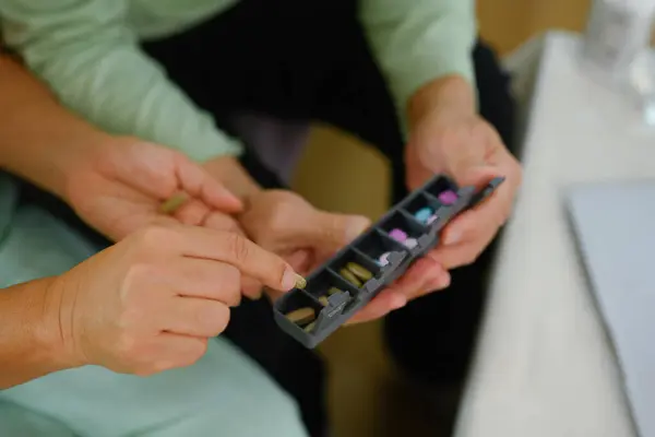 錠剤オーガナイザーに丸薬を入れた年配の女性 ヘルスケア 治療のコンセプト ストック画像