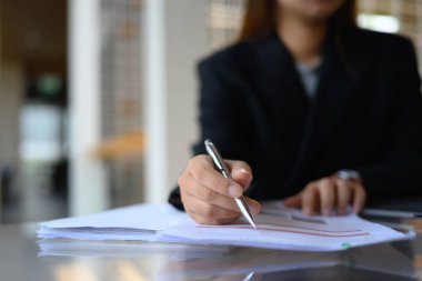 İşkadını el yazısı üzerine odaklanmış, ofis masasındaki kağıt işi belgelerini doldurmuş..