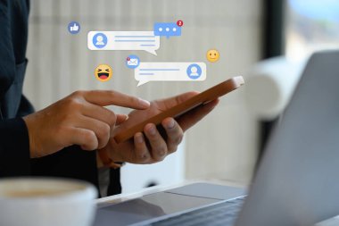 Bildirim simgeleriyle cep telefonu kullanan genç bir kadın, çevrimiçi toplulukta yorum yapıyor.