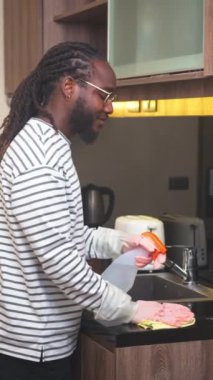 Mutfak tezgahını temizlik spreyi ve bezle temizleyen koruyucu eldiven giyen mutlu Afrikalı adam..
