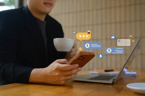 Jungunternehmer Trinkt Kaffee Und Chattet Sozialen Netzwerken Auf Seinem Smartphone Stockbild