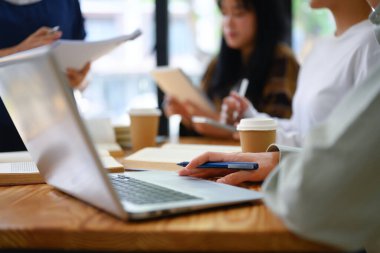 Üniversite öğrencileri kütüphanedeki görevlerinde birlikte çalışırken dizüstü bilgisayar kullanıyorlar..