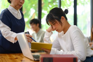 Bayan öğretmen, sınıf ödevini kötü yaptığı için üniversite öğrencisini azarlıyor..