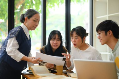 Üniversite öğrencileri öğretmenlerinin yardımıyla ödevlerini yapmaya çalışıyorlar..