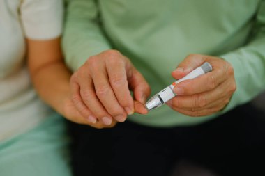 Kıdemli kocanın evde kan şekerini ölçerken karısına yardım ettiği görüntüler. Sağlık hizmeti kavramı.