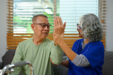 Evde profesyonel fizyoterapistle egzersiz yapan yaşlı bir adam. Rehabilitasyon ve Sağlık Konsepti.