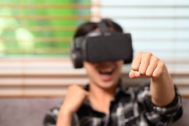 Neşeli genç adam evde sanal gerçeklik kulaklığıyla boks oynuyor..